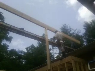 Carpenter setting a ridge beam over a new addition frame — Ice Dam Removal by Roofing Brothers in Harpursville