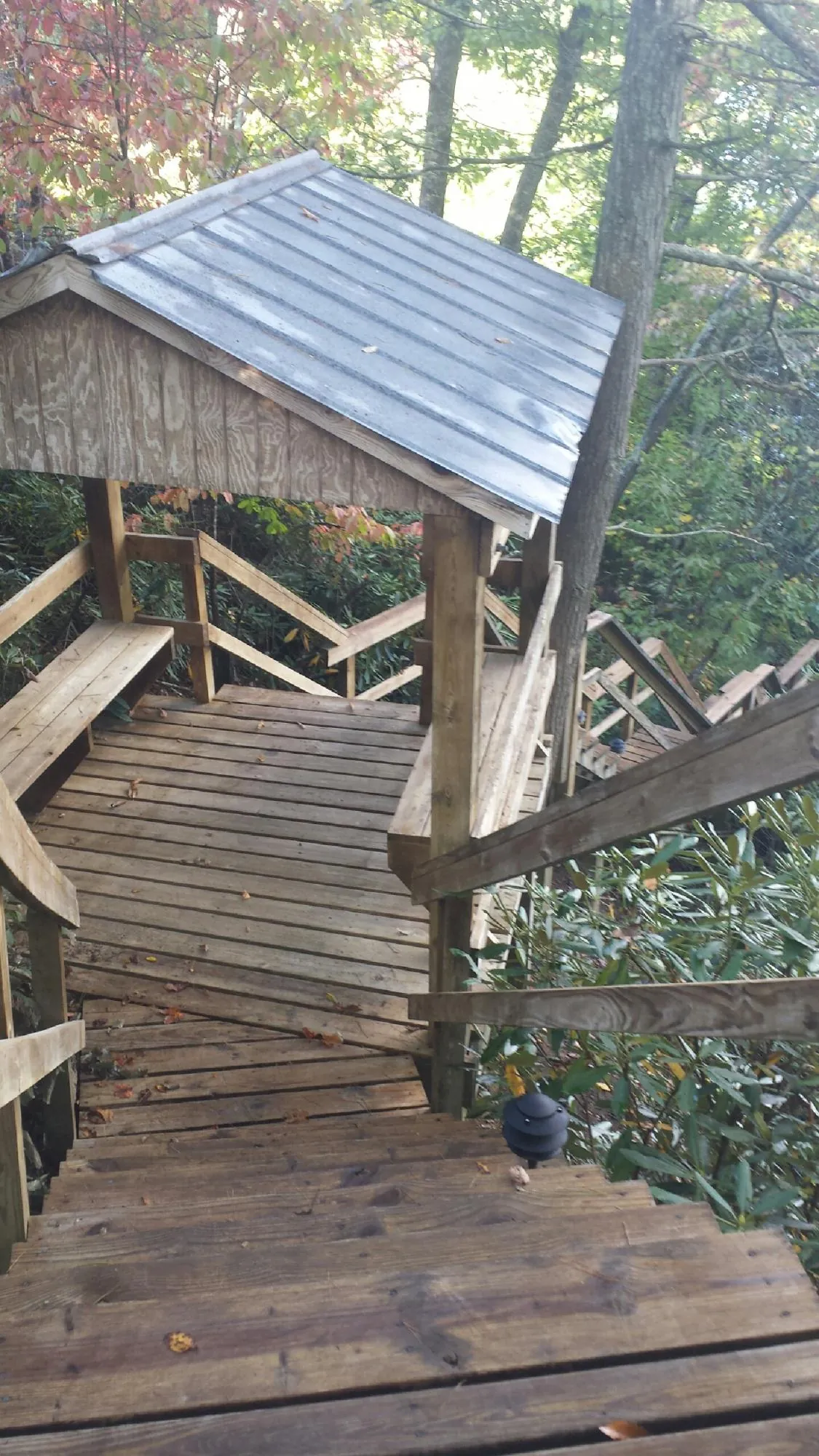Metal roofed shelter over wooden steps on a wooded walkway — Skylight Repair & Installation work by our crew in Harpursville