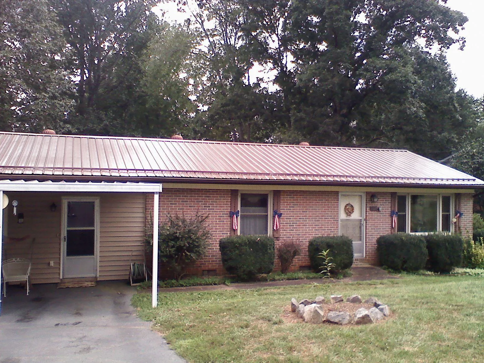Bronze metal roof and carport on a brick ranch home — Roof Repair work by our crew in Harpursville