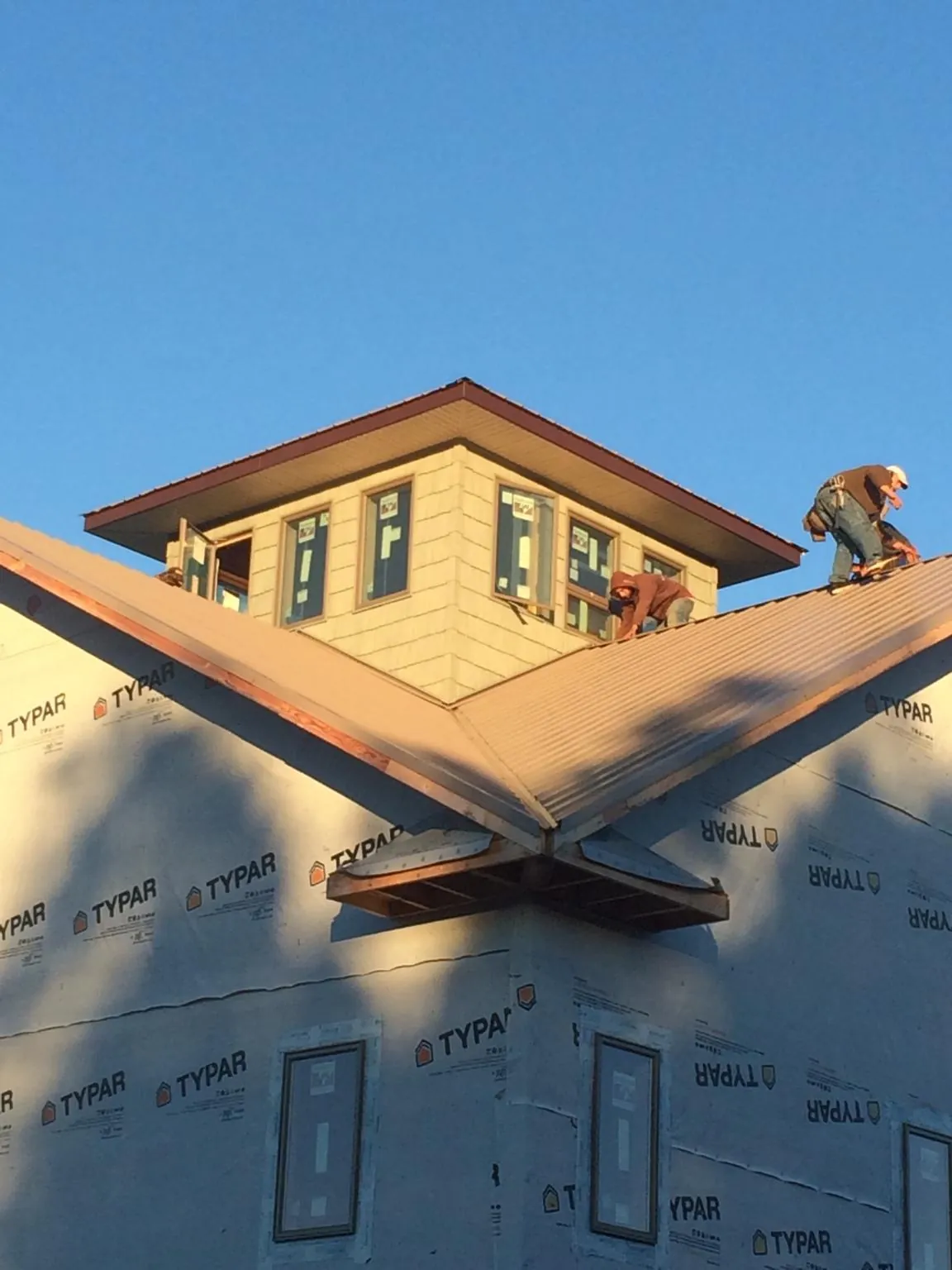 Roofers working around a rooftop cupola on a new metal roof at sunset — Roof Waterproofing in Harpursville by Roofing Brothers